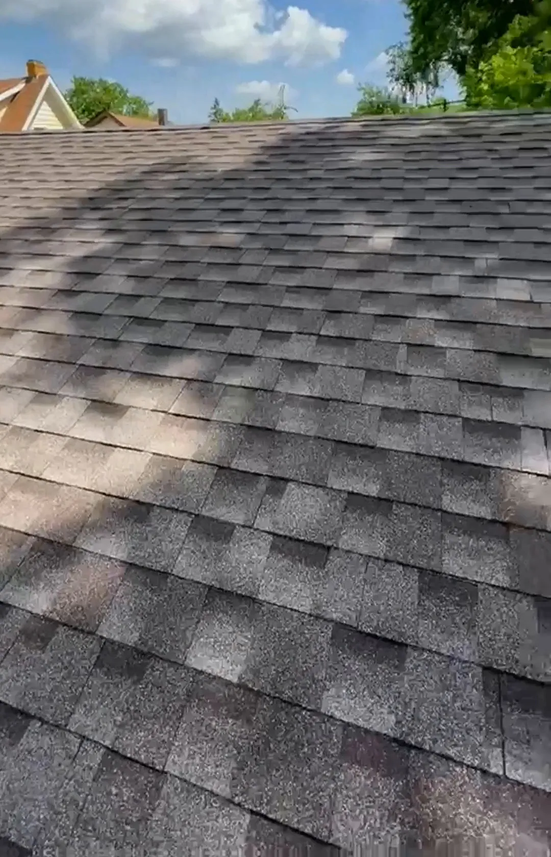 New roof after replacement: rows of new architectural shingles under a blue sky